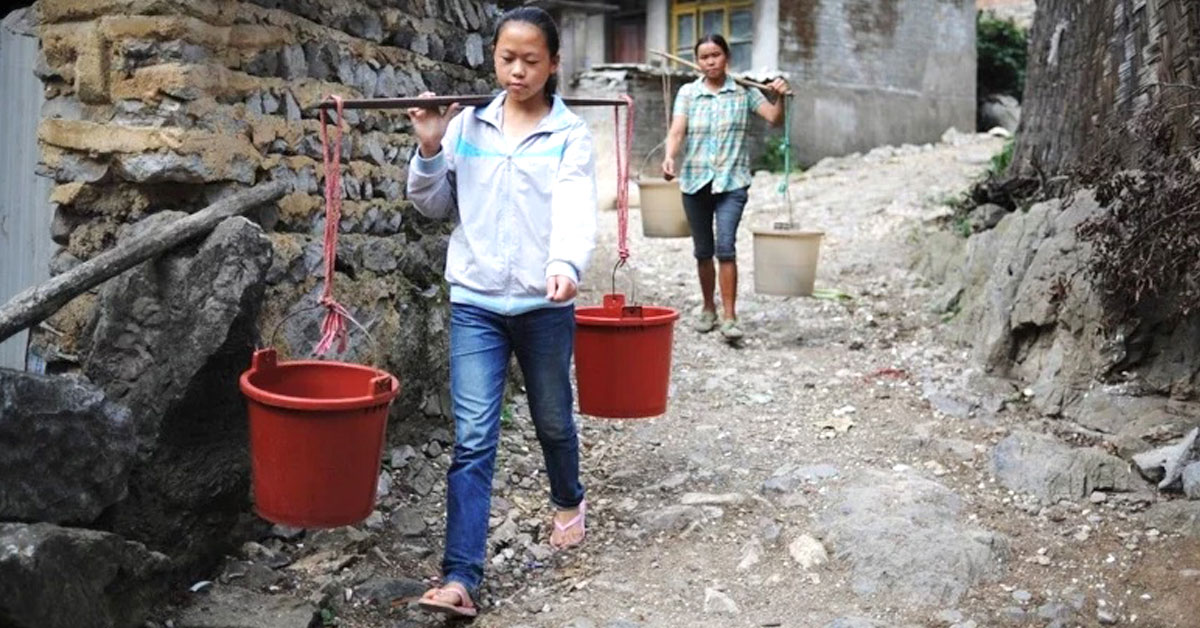 贵州黔南惠水县龙井村，两名女子挑着水桶去接水。
