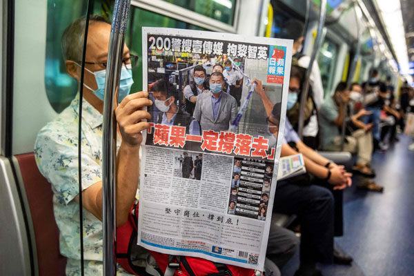 市民在香港地铁内，阅读《苹果日报》。（法新社）