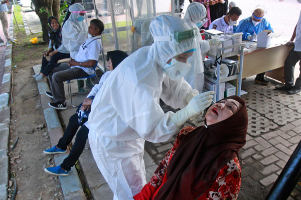棉兰医护人员为一名女子采取检体作病毒检测。