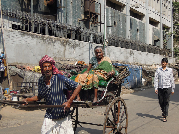 印度贫富悬殊，低下阶层似乎永远活在落魄的旧社会里。在印度仍可见到人力车，其后一系列塑料布下，正是一户户赤贫人家的窝居。