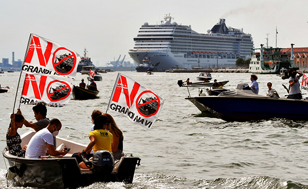 民众驾驶小艇举旗示威，反对巨型邮轮重现威尼斯。远处为9.2万吨重的“管乐号”邮轮。（法新社）