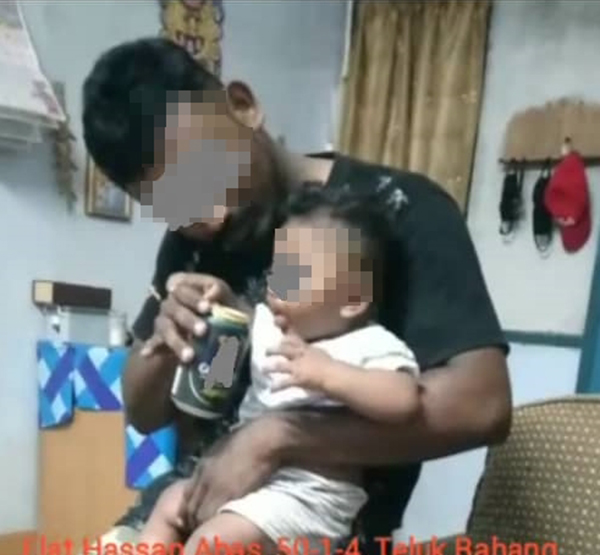一名男子抱着婴儿，疑是喂婴儿喝酒。