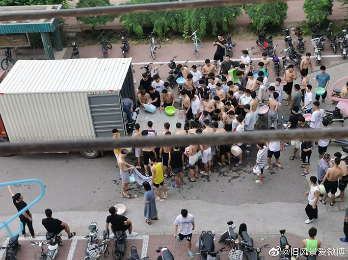 工作人员在货车上派发冰块，大批打赤膊的男学生手持容器在旁等候。