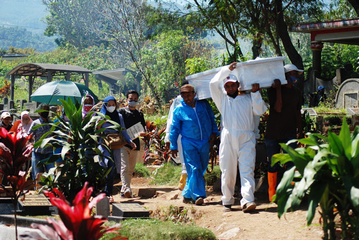 周日在印尼西爪哇万隆，殡葬人员准备将新冠患者遗体埋葬。（法新社）