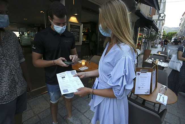 法国科西嘉城市利勒鲁斯一家餐馆老板，检查客人的健康通行证。（法新社）