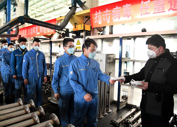 中国企业复工加强防疫措施。图为2月9日山东青岛城阳区一企业车间内，工人排队领取口罩。（新华社）
