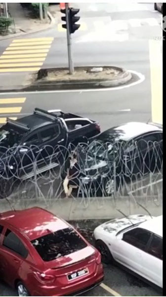 女子站在铁蒺藜前,不断东张西望。