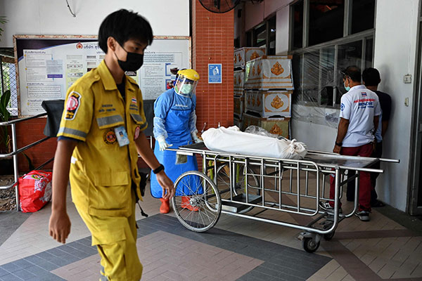 周六在泰国巴吞他尼府一家医院，医护人员将一具遗体推进停尸房。（法新社）