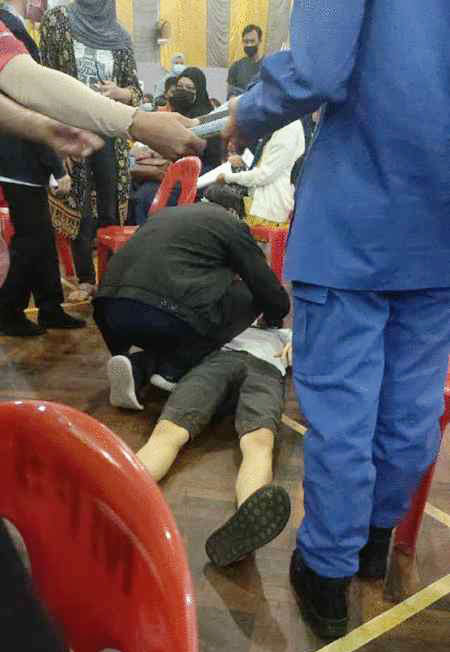 流传图片显示一名男子在接种中心晕倒，医护人员上前检查。（取自网络）
