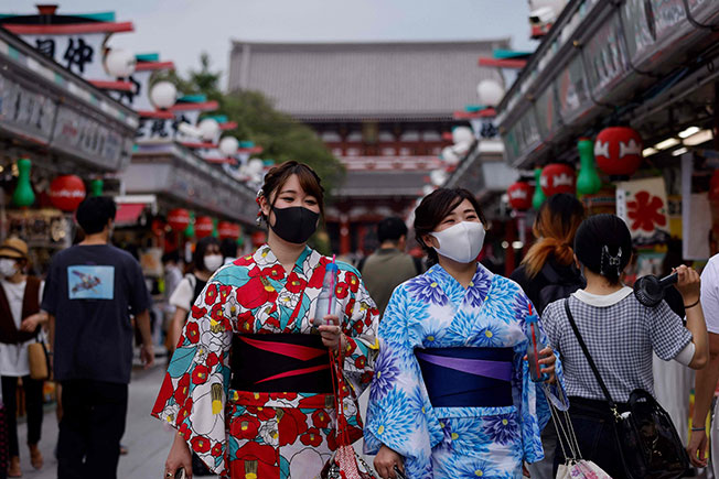 身着日本传统夏季服装、戴上口罩的女子12日在东京浅草寺逛街。（法新社）