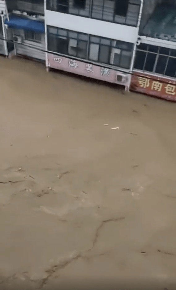 土黄色泥水淹到大街上，一楼的店家只剩下招牌还露出水面。