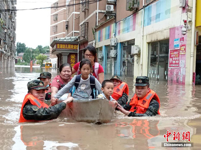 武警官兵深入湖北随州灾区，用小船协助受困灾民撤离。（中新网）