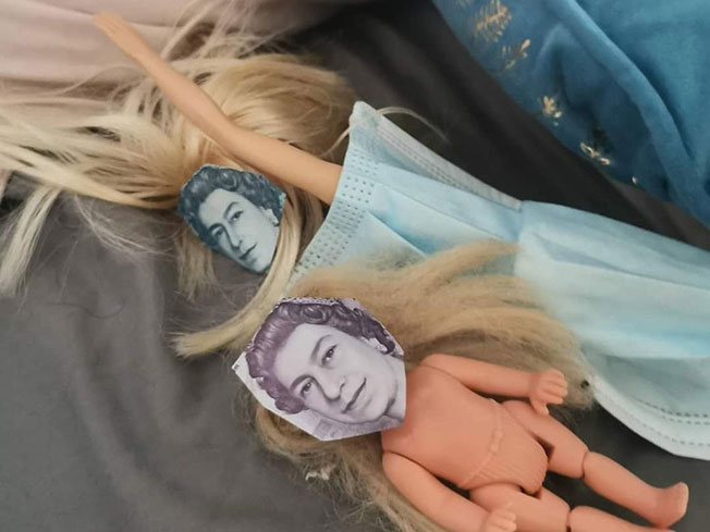 小女孩嫌芭比娃娃不够美丽，用钞票上英女王头像遮盖芭比脸部。