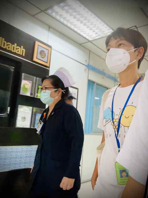  陈彦妮（右）跟着护士前往了解新冠肺炎病楼的情况。