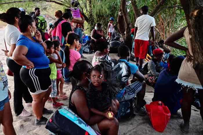 墨西哥一侧的非法移民坐在里奥格兰德河岸边，等待涉水进入美国。（法新社）