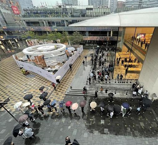 北京三里屯苹果商店门外，市民冒雨排起长队，购买苹果新品。