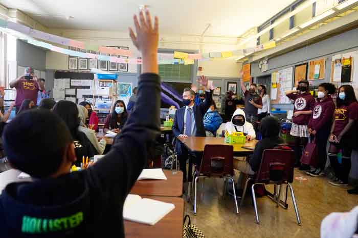 加州州长纽森（中）周五视察旧金山詹姆斯登曼中学，并进入教室与7年级科学班的学生交流。（美联社）