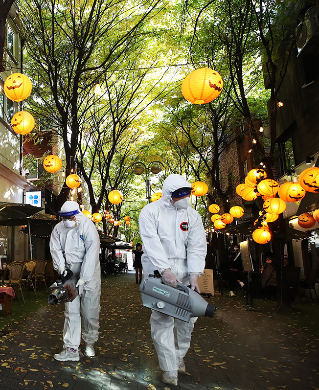 首尔街头挂着万圣节装饰，卫生人员周三为防疫做好消毒。（欧新社）
