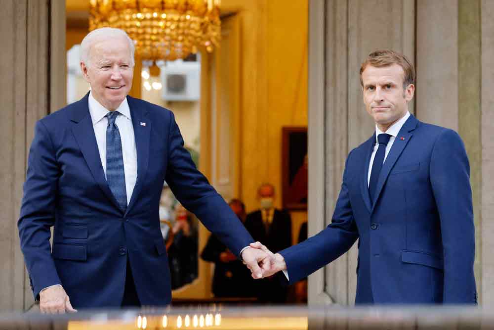 美国总统拜登（左）与法国总统马克龙握手，冰释前嫌。（法新社）