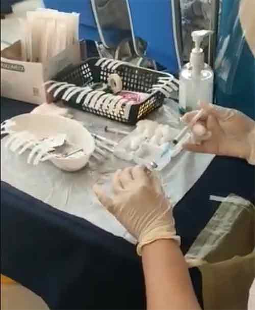 医护人员把盐水注入一小瓶的疫苗液里。