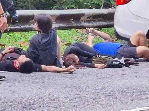 受伤的Bezza轿车司机和乘客躺在路旁，等候救护车到场。