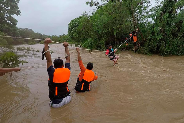 台风“圆规”带来暴雨和洪水，卡加延省的灾民冒险撤离灾区，沿着绳索涉水而过。（美联社）