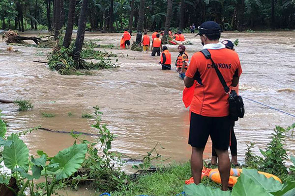 在巴拉旺省，救援人员协助灾民撤离灾区。（美联社）