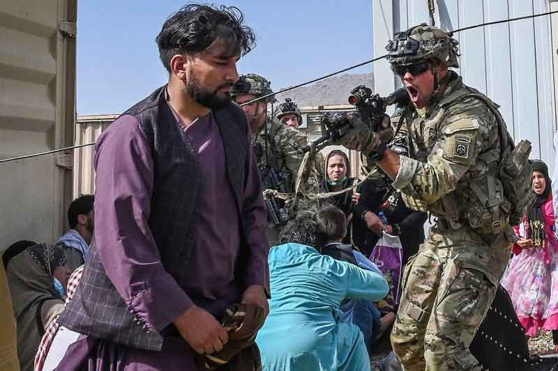 8月16日，为了控制混乱失控的局面，一名美军拿枪喝斥想要强行闯入机场的阿富汗男子。
