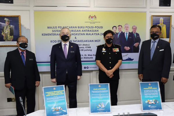 魏家祥（左）推介《马来西亚交通部反贪管理系统政策与道德行为准则》书籍；左起是亨利松艾贡、阿占峇基及依斯汉依萨。