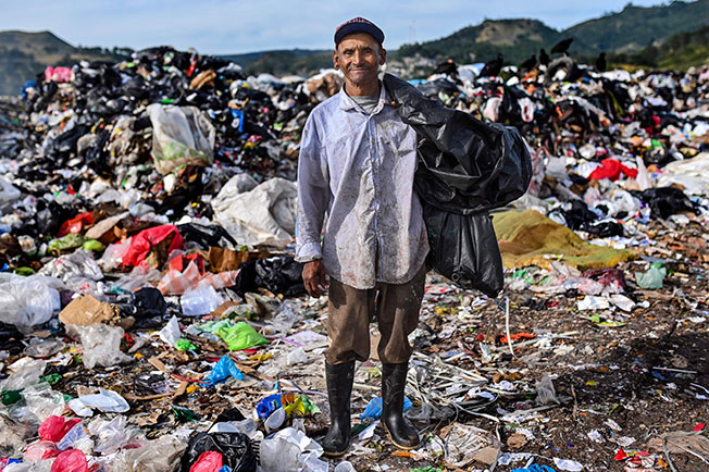 艾斯柯托在垃圾堆中拾荒维生，他一边挑拣塑胶和金属碎片变卖，一边试着驱赶秃鹫。（法新社）