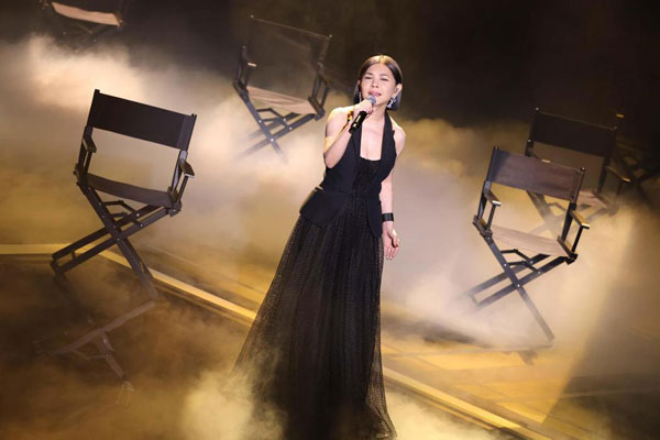 张清芳站在导演椅中间演唱。