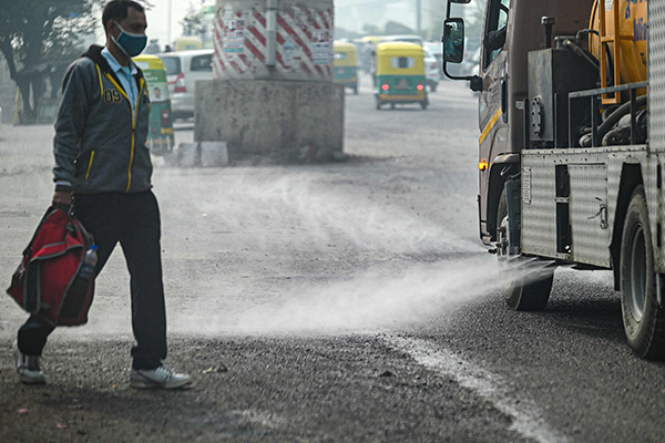 东德里市政公司车辆12日在街道喷水，减少尘埃飘扬。（法新社）