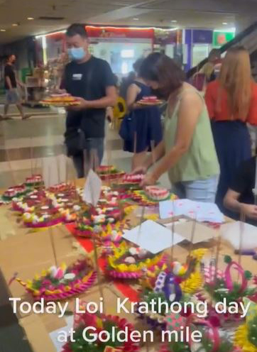 有摊位在售卖装饰着鲜花和蜡烛的花灯，数位民众在摊位前排队等待。（视频截图）
