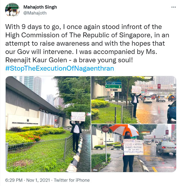 两名大马律师在新加坡驻马最高专员署外冒雨高举大字报，促请大马政府介入，解救即将服刑的纳加恩德兰。