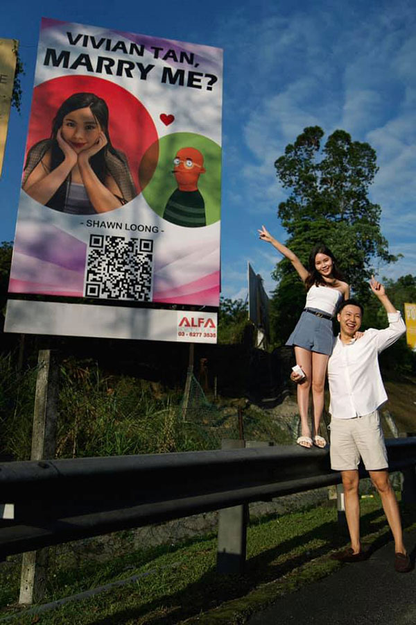 陈俐君与男友在广告板前拍照留念。