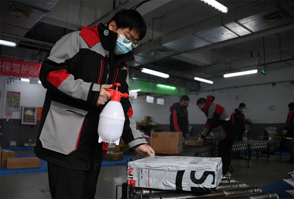 中国北京海淀区时隔半个月又出现新冠阳性反应者。图为11月20日海定区快递业者加强消毒包裹作业情景。