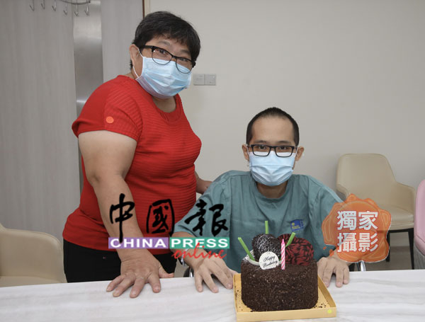 林丽玉（左）为邱炜杰送上生日蛋糕，为他庆祝生日。