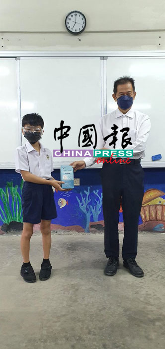 柔佛巴力古麻育英华小校长黄炳成（右）移交防疫物资给受惠学生。