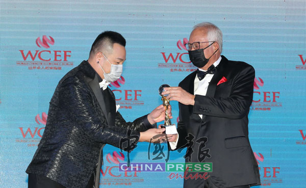 林德荣（左起）从纳吉手中接过世界华人杰出主持人奖。