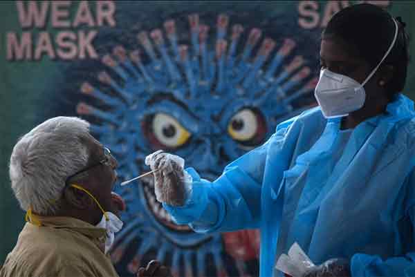 Omicron在全球各地陆续现踪，图为印度清奈市卫生人员3日在火车站为抵达的旅客采集咽喉拭子样本检疫。