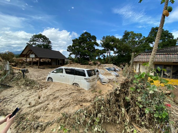 锺志海一家32口分开着7辆轿车泊在度假村入口处集合，全被洪水淹过顶，现场如同海啸过境般，一片狼藉。