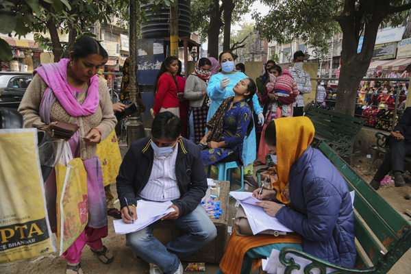周日在克什米尔闹市，卫生人员为民众做新冠病毒检测。（美联社）