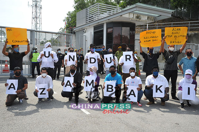 公青团举起“阿占峇基下台”纸牌，促请陷入超额持股争议的阿占峇基辞职。后排右为马智礼。