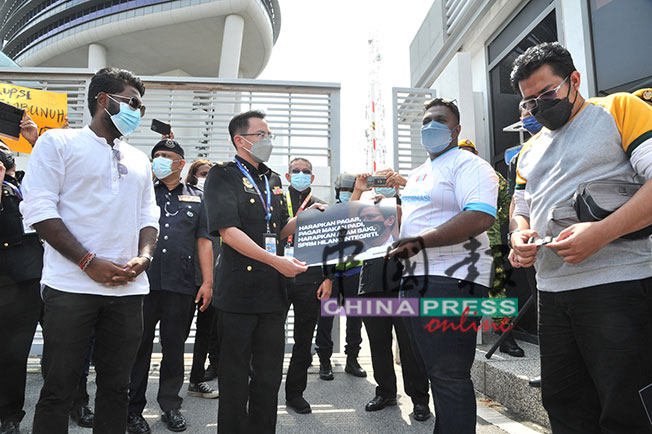 迪班苏博马廉（右2）将印有马来谚语“监守自盗”的纸牌移交给反贪会执法官范星丰。