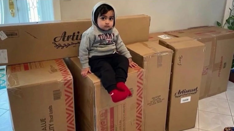 男童坐在自己网购的家具箱子上。