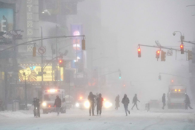 民众周六在暴风雪中走过纽约时报广场。（美联社）