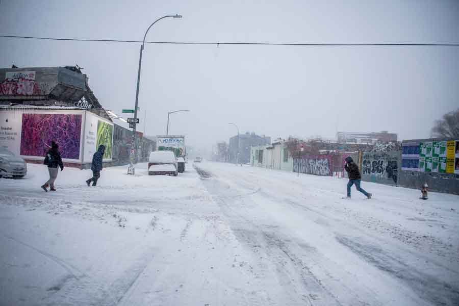 纽约布鲁克林区民众近日在大雪纷飞中路过马路。