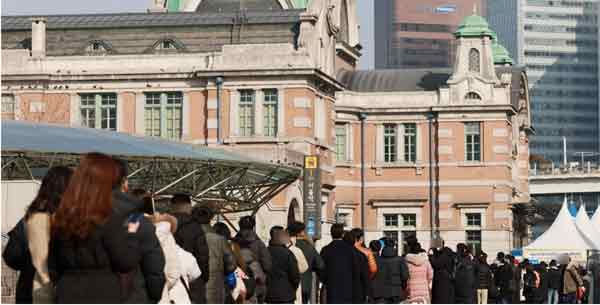 韩国民众27日在首尔火车站广场的临时筛查诊所排队等待接受病毒核酸检测。