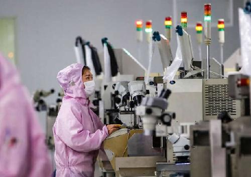 2020年2 月16日，员工戴着口罩和防护服在江苏省泗洪市的一条智能芯片生产线上工作。（法新社）