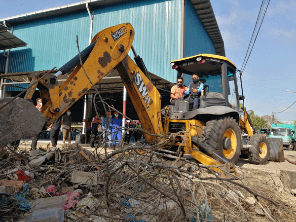 依斯迈阿都慕达（右）协助清理灾区的庞大垃圾量。